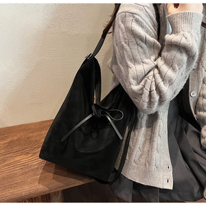 Detail view of black suede bucket bag with ribbon bow, showing upscale commute style