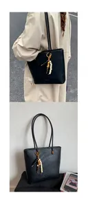 Detail view of black tote bag with textured leather and decorative beaded strap charms