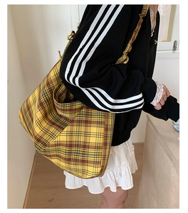 Side view of large yellow plaid canvas tote bag worn by model in casual interior
