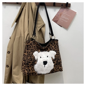 Detail of leopard print tote bag with plush dog patch hanging on a wooden hanger