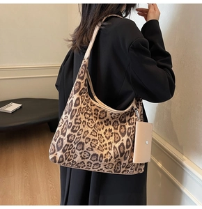 Detail of large leopard print hobo bag with side pouch shown on a model's shoulder