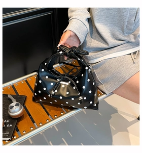 Close-up of black leather dumpling bag with white polka dots and a knotted handle