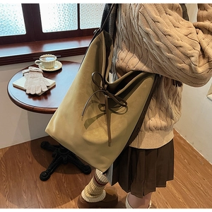 Detail of olive green suede tote bag with elegant bow tie decoration and leather handles