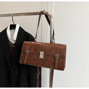 Detail of vintage brown shoulder bag showing faux leather texture and metal swivel lock