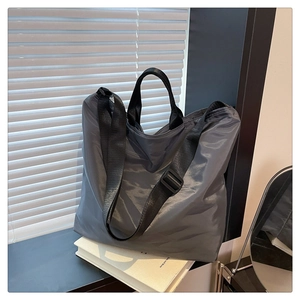 Detail of waterproof nylon tote bag with wide strap and minimalist gray fabric texture