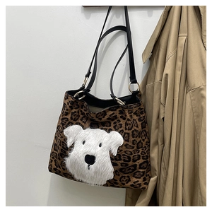 Detail of leopard print tote bag featuring a plush white puppy patch and golden hardware