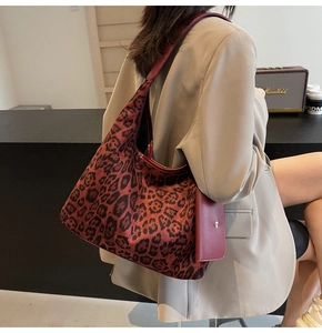 Detail view of large leopard print tote bag with attached small red rectangle purse