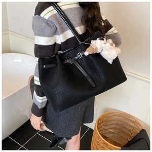 Détail du sac cabas tressé noir avec bandoulière et breloque ours en peluche