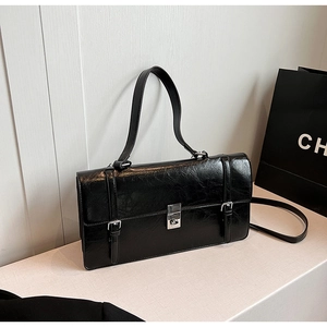 Detail of glossy black leather handbag with silver twist lock and retro business style