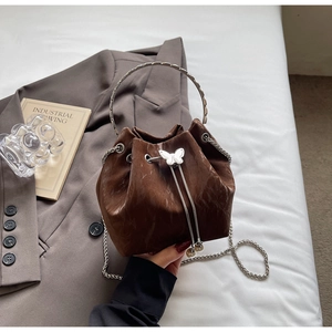 Détail d'un sac seau marron à motif marbré avec fermoir papillon argenté et poignée ronde
