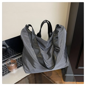 Close-up of metallic grey waterproof tote bag with dual handles and black shoulder strap