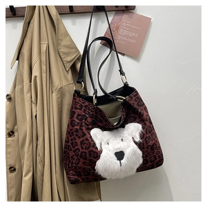Detailed view of red leopard tote bag with plush puppy patch on wooden hanger