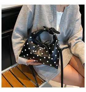 Close-up of black polka dot dumpling bag featuring a knotted handle and silver metallic charms