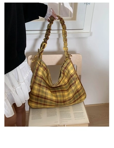 Detail of vintage yellow plaid shoulder bag with stylish scrunchie strap on a chair