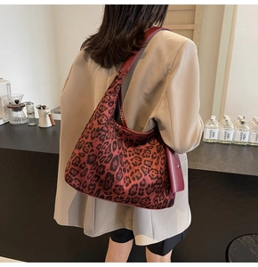 Detail of vintage leopard print tote bag with burgundy leather trim worn by model