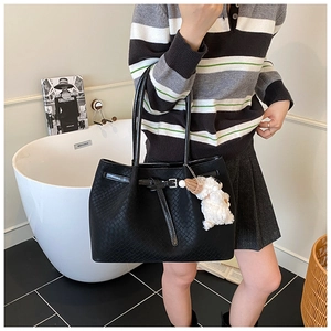Détail du sac cabas tissé noir avec boucle réglable et breloque mouton en peluche blanche