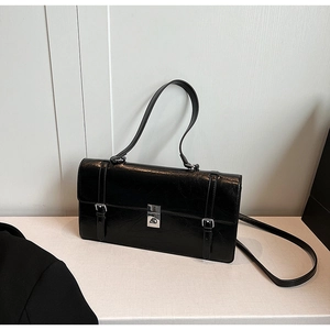 Detail of black glossy wrinkled leather texture and silver metal twist lock on shoulder bag