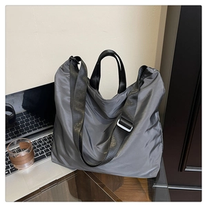 Close-up of a large grey waterproof tote bag with adjustable strap in a workspace setting