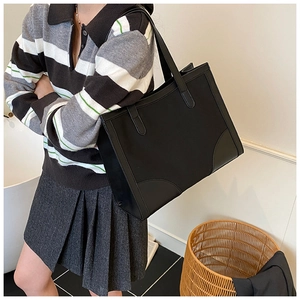 Détail du grand sac cabas en cuir noir montrant sa capacité et sa bandoulière minimaliste