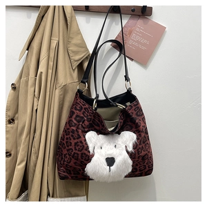 Detail of red leopard print tote bag with plush schnauzer decor and leather strap