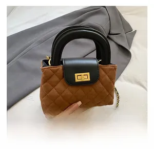 Detail of brown quilted suede handbag with black leather flap and golden rotary lock