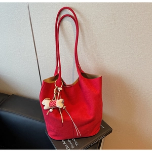 Detail of red large capacity tote bag with long shoulder straps and white puppy charm