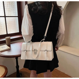 Detail view of white PU leather shoulder bag with silver buckles and adjustable strap
