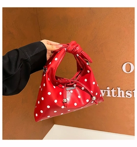 Detail of red polka dot handbag with knotted handle and silver drawstring beads