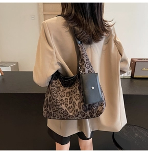 Detail of leopard print tote bag with small black leather pouch on a female model