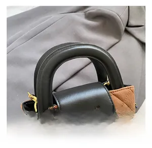 Close-up of brown quilted suede texture with gold twist lock and black leather handle