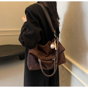 Vue latérale du grand sac cabas en daim marron avec anses en cuir et pendentif de baseball