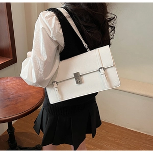 Detail of white embossed leather shoulder bag featuring silver turn-lock and vintage straps