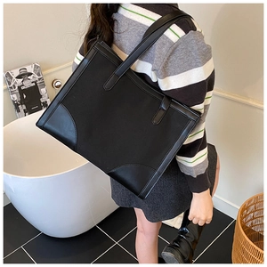 Détails des coins inférieurs renforcés d'un grand sac cabas noir en cuir synthétique
