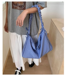 Detail of blue plaid tote bag with pleated scrunchie strap and side bow accents