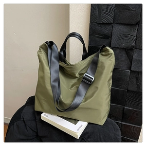 Detail view of large army green waterproof nylon tote bag with black webbing straps
