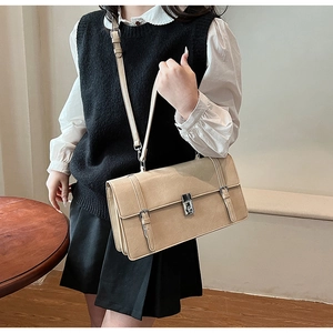 Detailed view of beige faux leather shoulder bag with vintage buckles and metal lock