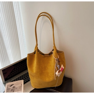 Mustard yellow suede tote bag with cute animal charm on leather seat background