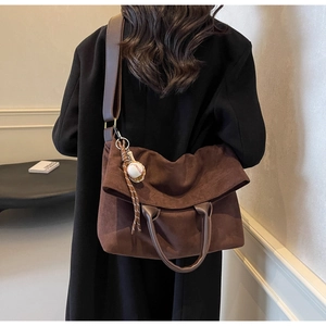 Detail view of large dark brown suede tote bag with unique baseball charm accessory
