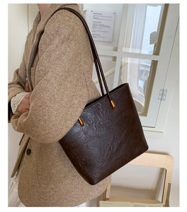Detail of dark brown tote bag with wrinkled leather and gold hardware on model