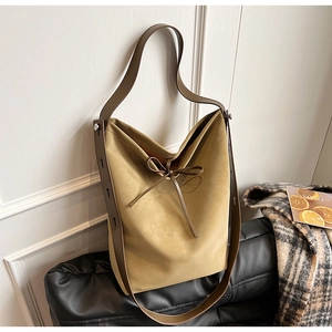 Detail of yellow suede tote bag with brown leather strap and bow tie decoration