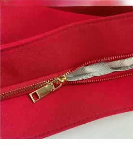 Macro view of smooth light gold metal zipper on premium red textured tote bag fabric