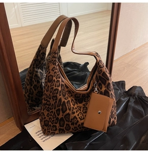Detail view of leopard print tote bag with brown leather strap and small accessory pouch