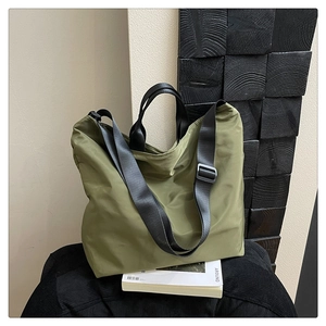 Detail of army green nylon tote bag featuring durable black handles and adjustable strap