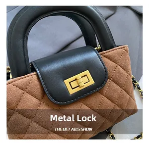 Detail of golden hardware lock on brown quilted suede bag with black leather handle