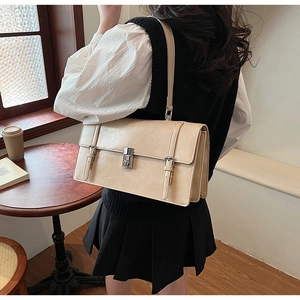 Detail of cream minimalist shoulder bag with vintage metal lock and faux leather texture
