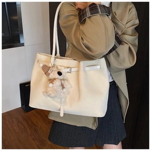 Détail du cabas en cuir blanc avec texture litchi et adorable breloque chiot en peluche