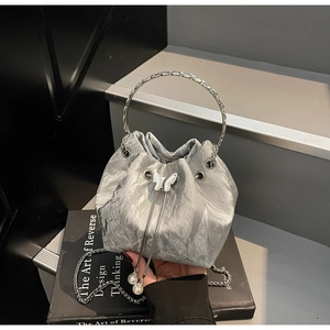 Détail du sac seau argenté avec tissu plissé métallique et breloque en perle