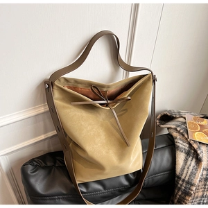 Detail of khaki suede bucket bag with brown leather trim and bow tie closure