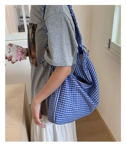 Detail of blue and white plaid canvas hobo bag with stylish ruffled shoulder strap design