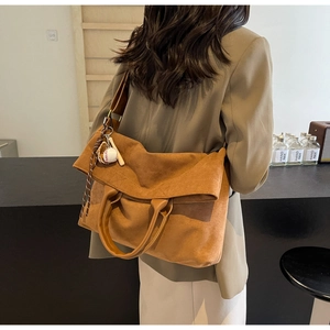 Detailed view of brown suede tote bag featuring adjustable strap and baseball charm